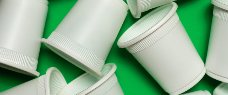 Bioplastic cups on a green background