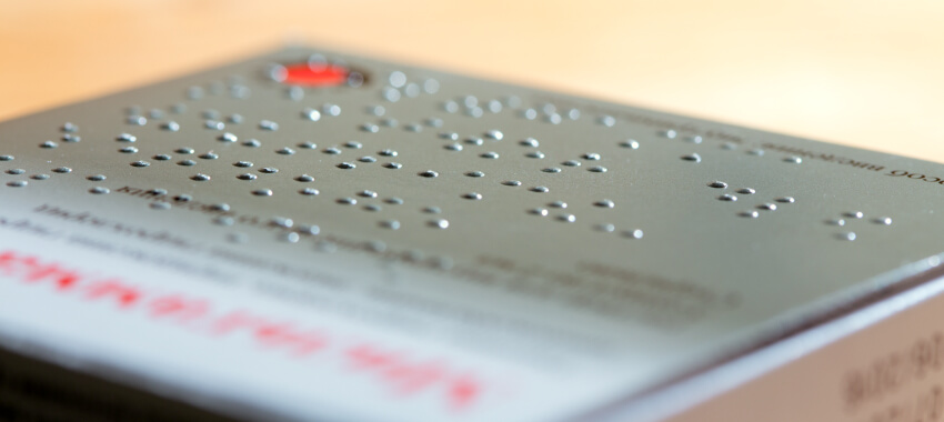 Close-up of embossed braille text on premium metallic silver business card with red accent details