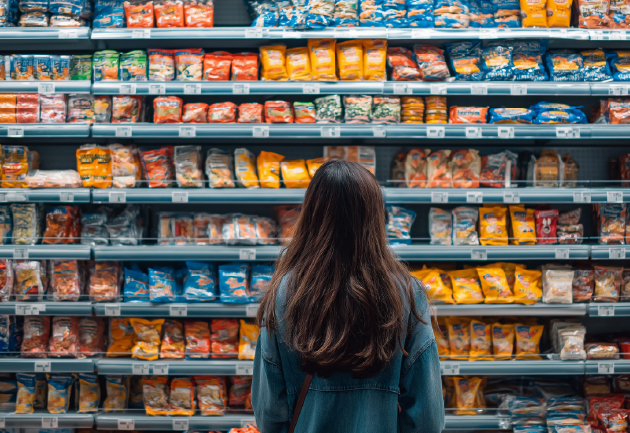 A shopper facing extensive shelving of packaged food products, emphasizing the overwhelming presence of packaged goods in retail environments.