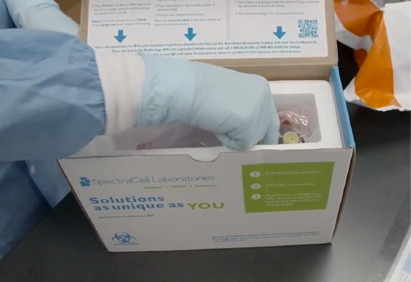 A gloved hand unpacking SpectraCell Laboratories medical specimen collection kit with instructions