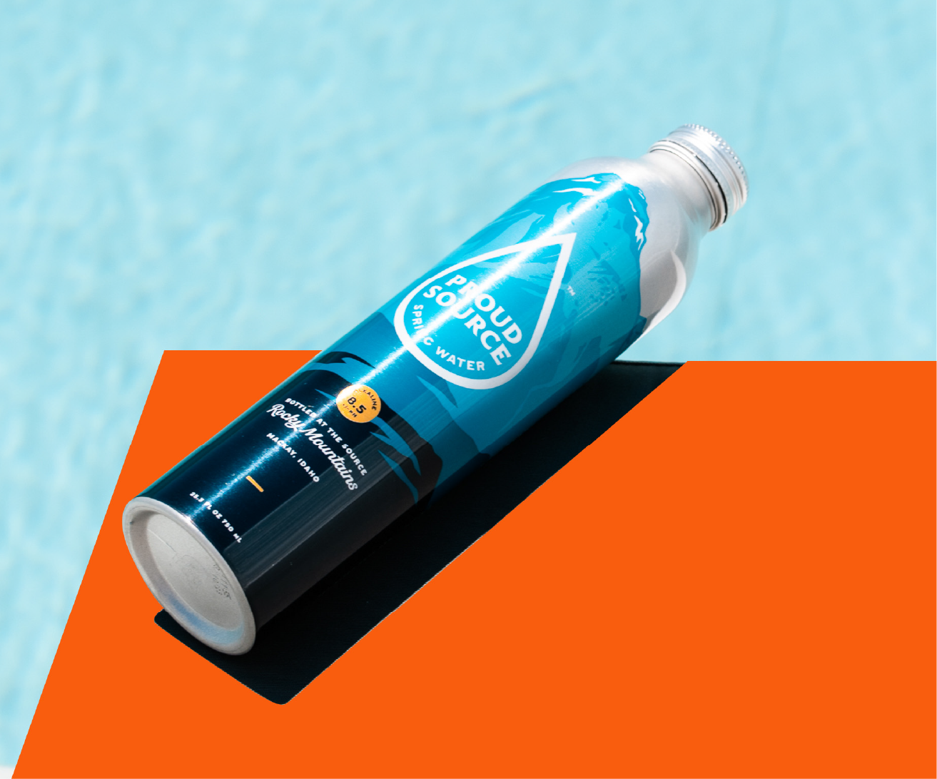 Blue Proud Source spring water bottle on orange surface