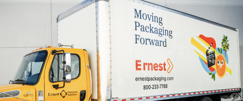 Yellow Ernest Packaging Solutions delivery truck with branded white trailer displaying company logo and contact information