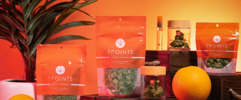 7Points hybrid cannabis products in orange transparent packaging displayed with oranges and plants.