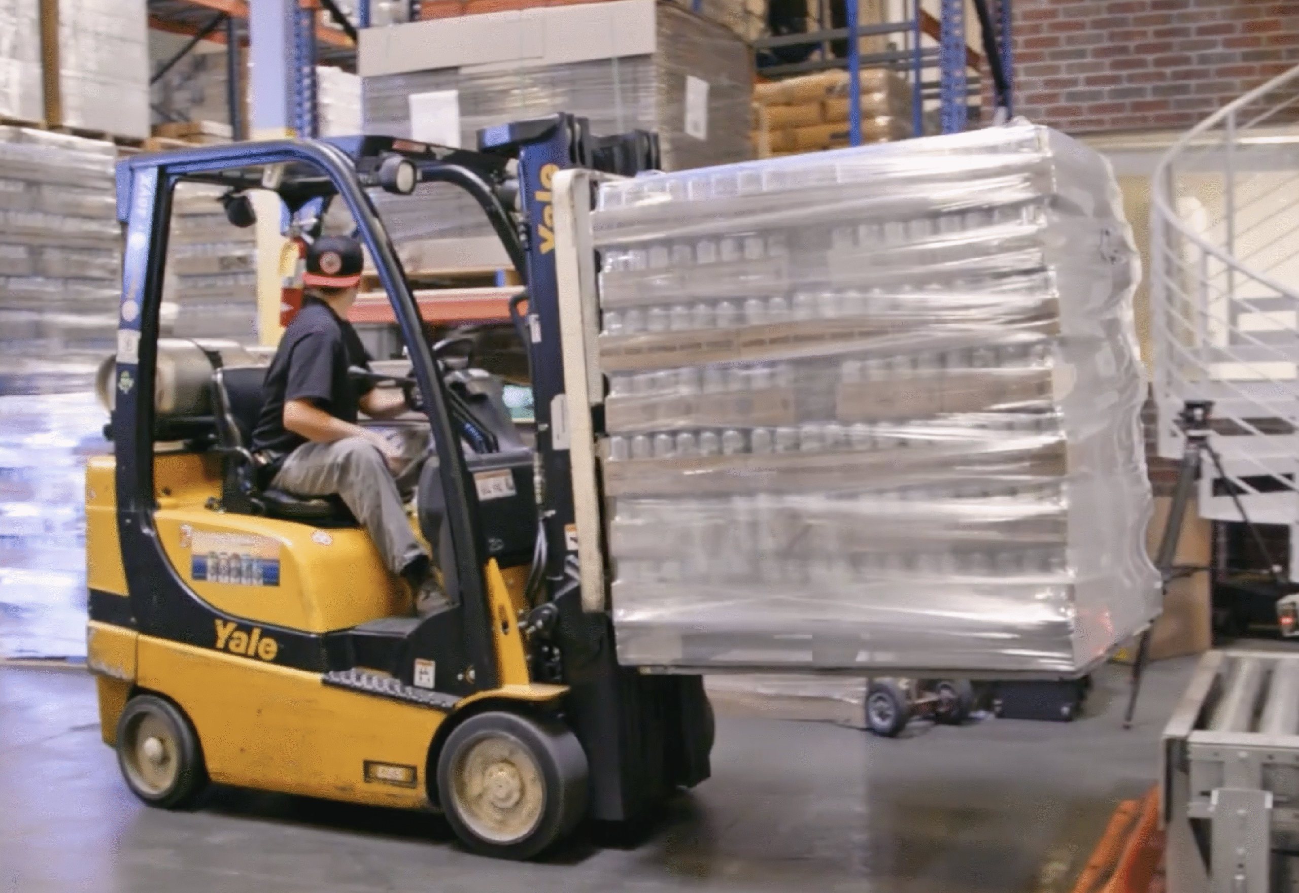 Rows of branded pharmaceutical boxes with red caps arranged on conveyor in fulfillment facility.