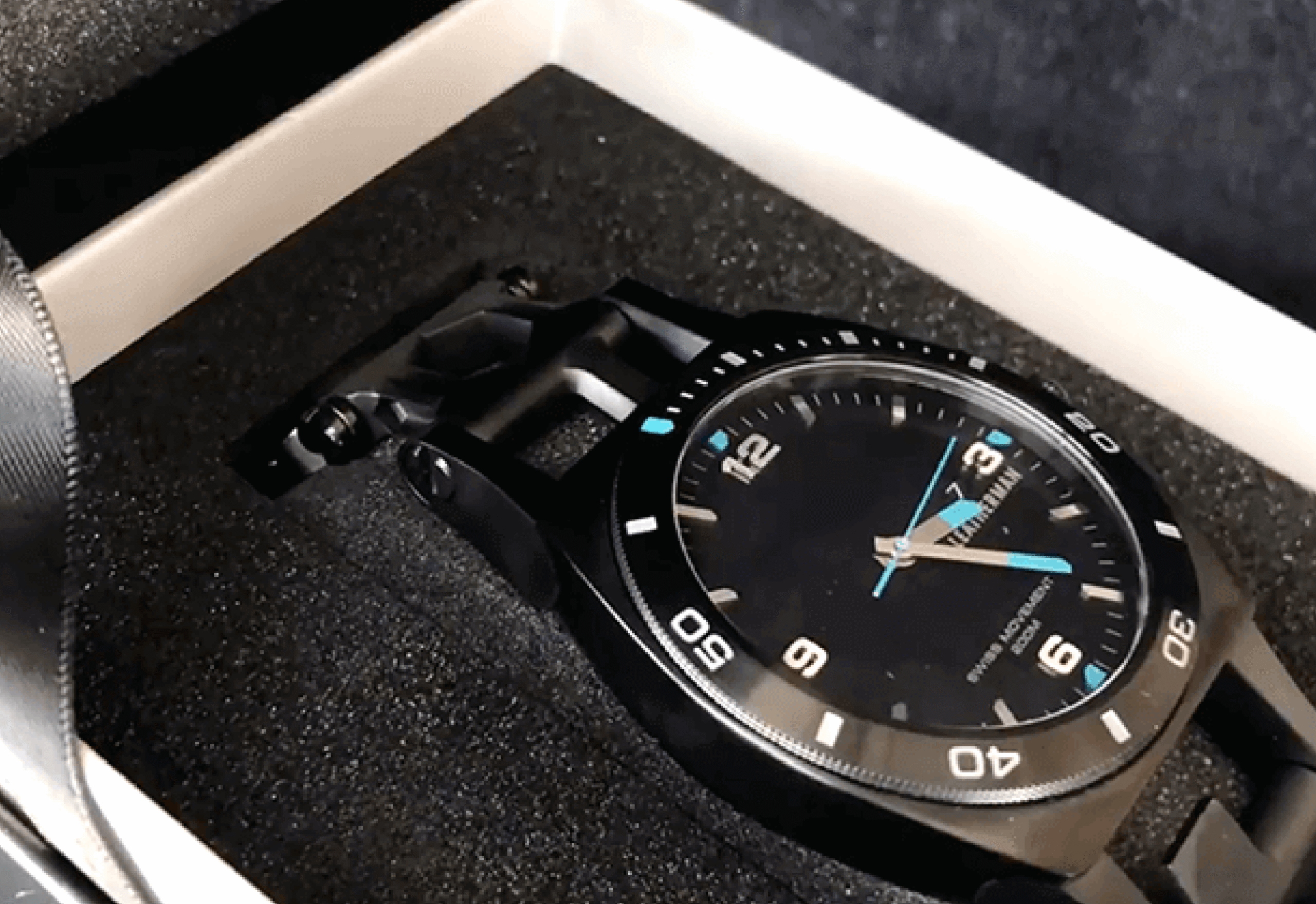 High-end black sports watch with blue accents nestled in custom foam packaging insert.