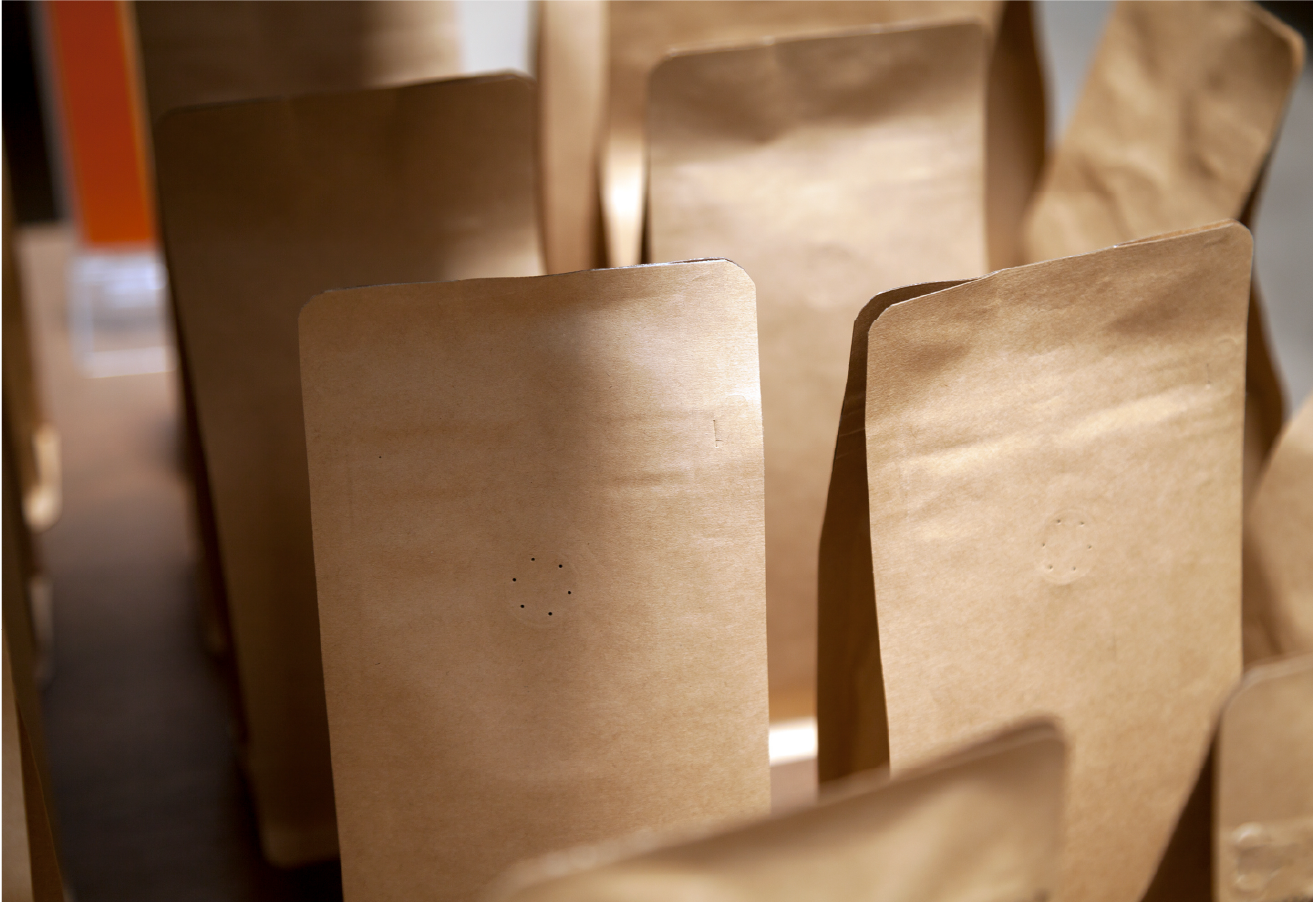 A close-up of multiple plain kraft paper stand-up pouches grouped together, highlighting their natural, eco-friendly material and flat-bottom gusset construction.