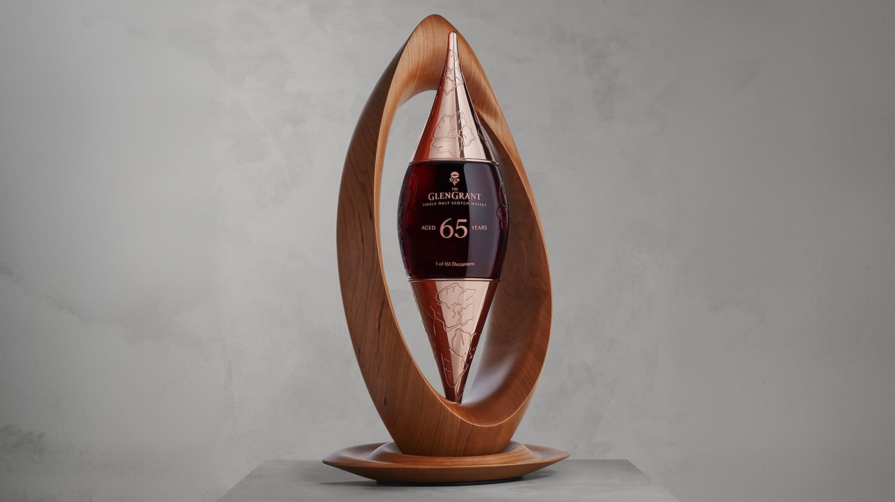 Glen Grant 65 Year Old single malt scotch whisky decanter housed inside a sculptural carved wooden display stand shaped like an elongated eye.