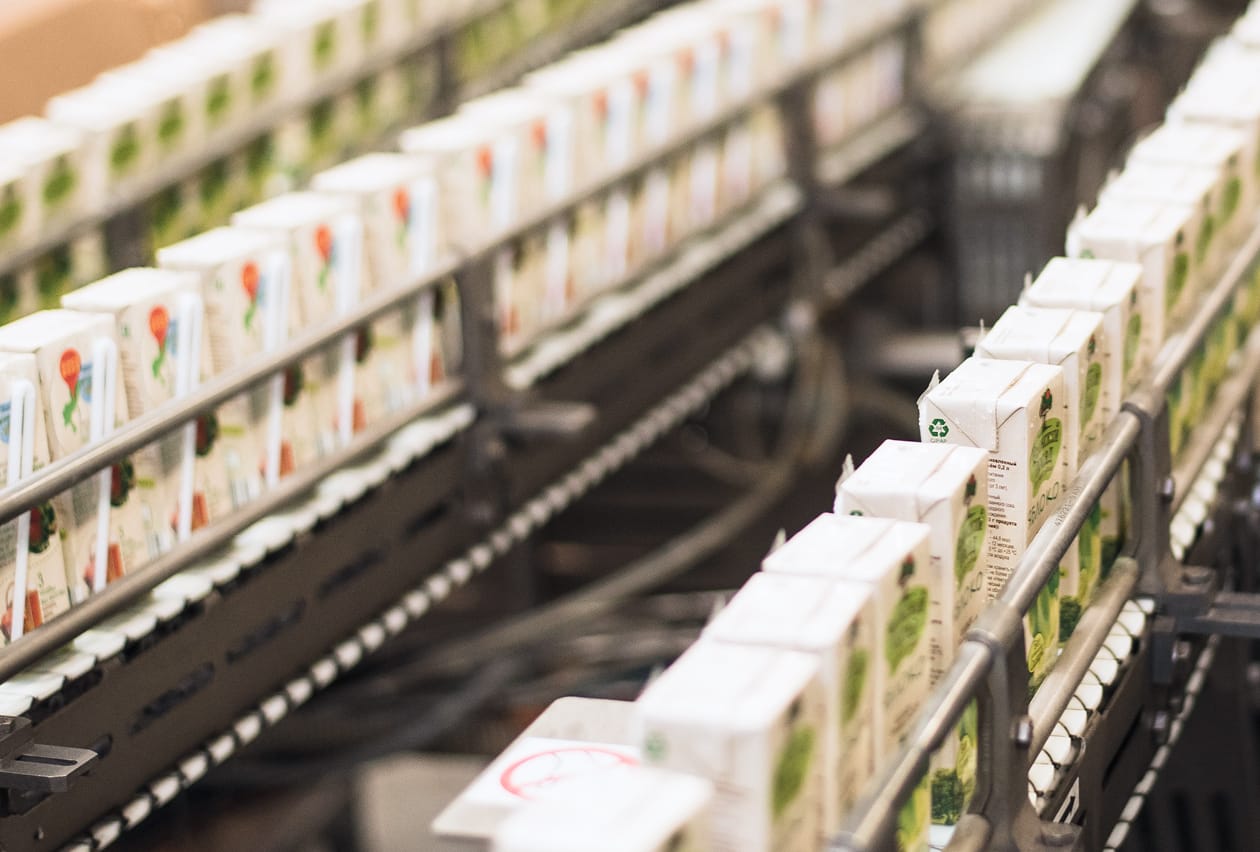 Rows of recyclable paperboard cartons moving along a production conveyor line.