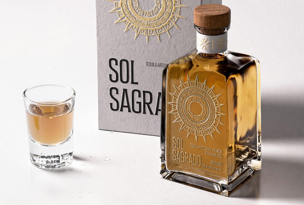 Sol Sagrado premium tequila in an embossed glass bottle with wood cap, beside a shot glass and gift box.